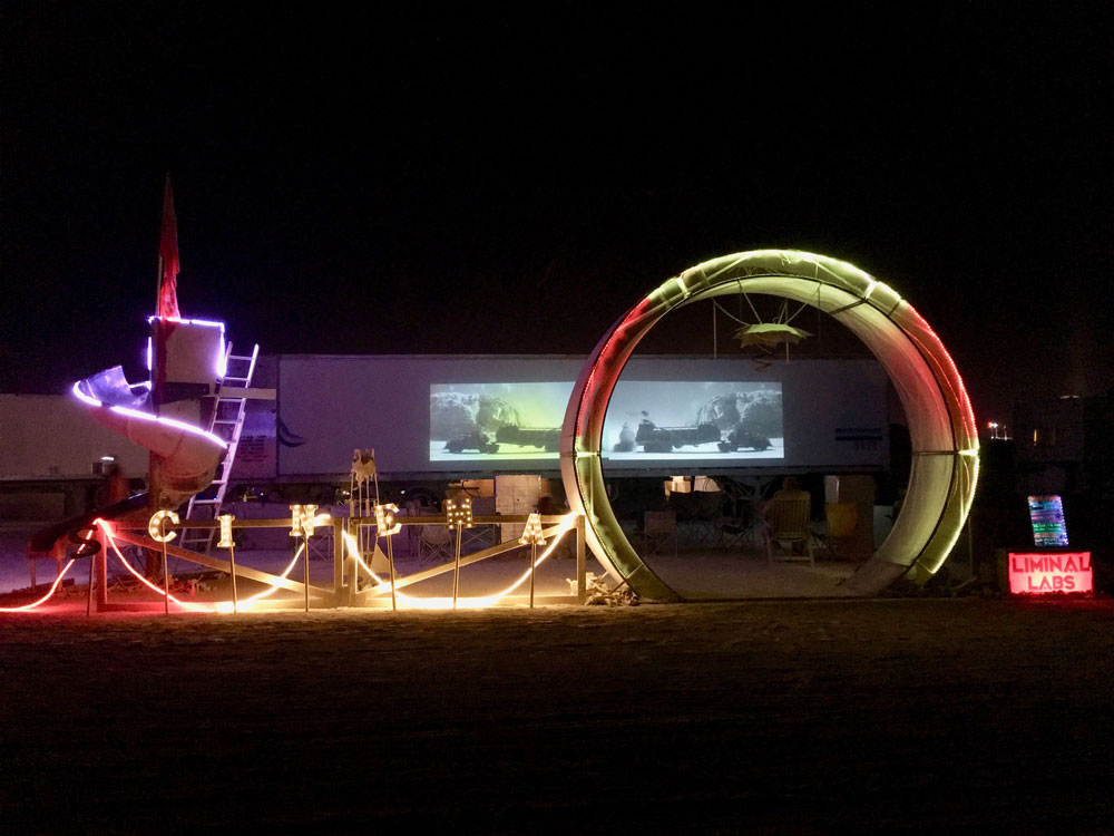"CINEMA" light-up letters (nighttime, from across street) at frontage of Liminal Labs camp